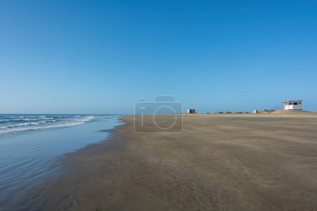 Plage de sable au bord de la mer avec vagues et ciel bleu