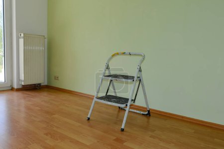 Old stepladder stands in a freshly painted empty room after renovation