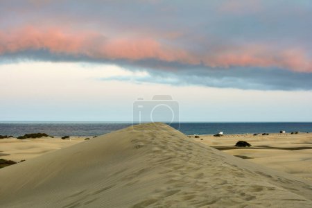 Dans les dunes de Maspalomas sur Gran Canaria en Espagne. Vue sur la mer dans la lumière du soir avec nuages et ciel bleu. Les immenses dunes de sable ressemblent à un petit désert et sont une réserve naturelle.