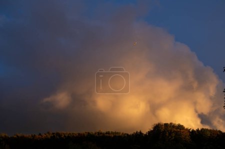 Foto de Nube amarilla grande en el cielo en el sol de la tarde sobre un bosque verde - Imagen libre de derechos