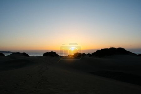 Dunes de sable et mer à Maspalomas au coucher du soleil sur Gran Canaria en Espagne. Les immenses dunes de sable ressemblent à un petit désert et sont une réserve naturelle.
