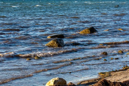 Grandes piedras yacen en el agua en la costa del Mar Báltico, con olas