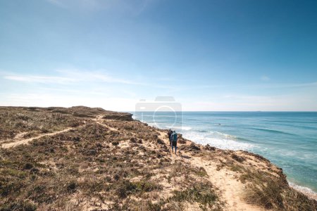 Foto de Aventureros apasionados caminan por la escarpada y seca costa con acantilados alrededor del Océano Atlántico en un sendero llamado Fisherman Trail en Portugal. - Imagen libre de derechos