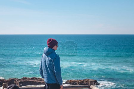 Foto de El turista disfruta de la vista desde un mirador en una playa de arena en la costa atlántica cerca de Vila Nova de Milfontes, Odemira, Portugal. Siguiendo los pasos de la Rota Vicentina. Sendero de pesca. - Imagen libre de derechos