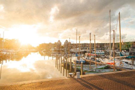 Téléchargez les photos : Coucher de soleil sur le port d'Almere, au centre des Pays-Bas. Transport par eau pendant l'heure dorée. - en image libre de droit