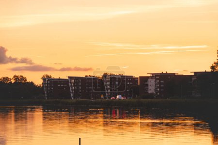 Photo for Perfect sunset on the shores of Lake Gooimer near Almere. The orange inferno illuminates the passing clouds and reflects on the calm surface. - Royalty Free Image