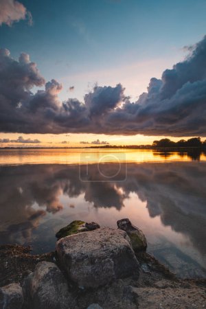 Photo for Perfect sunset on the shores of Lake Gooimer near Almere. The purple-orange inferno illuminates the passing clouds and reflects on the calm surface. Beauty of Netherlands. - Royalty Free Image