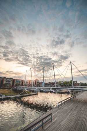 Photo for Pedestrian and bicycle bridge over the harbour in the centre of Almere during sunset. Dutch modern and utilitarian construction. - Royalty Free Image