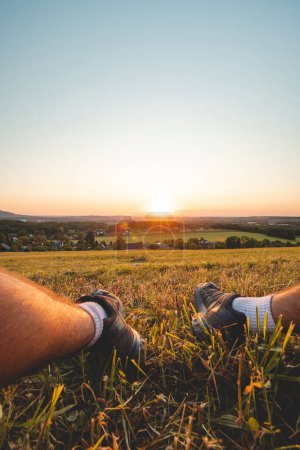 Téléchargez les photos : Les pieds du randonneur illuminés par la lumière rouge-orange du soleil, contre le ciel sombre. Beskydy mountains, République tchèque. - en image libre de droit