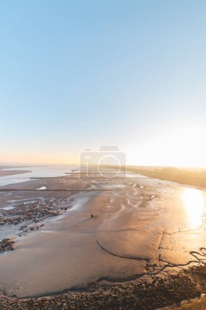 Seying shore at low tide of Plaat van Walsoorden at Ossenisse radar in the southern Netherlands under the bright orange-yellow glow of sunrise.