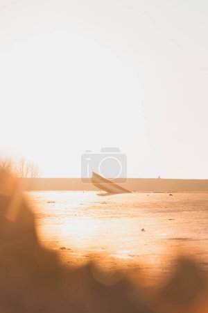 Hundimiento de barcos en arenas movedizas al amanecer en la costa de los Países Bajos. Últimos trozos de esperanza y vida. El resplandor naranja y el barco hundido.