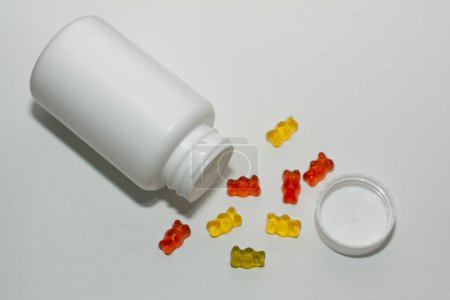 Téléchargez les photos : Pot de vitamines pour enfants ours gelée de couleur sur un fond blanc - en image libre de droit