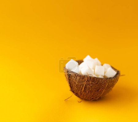 Kokoszucker, Zucker in der Kokosnussschale auf gelbem Hintergrund