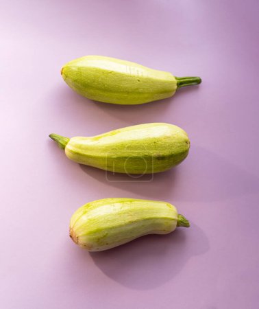 Photo for Three green zucchini on a soft purple background - Royalty Free Image