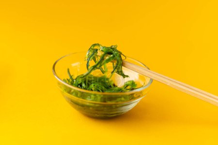 Téléchargez les photos : Salade chuka dans une assiette en verre avec baguettes - en image libre de droit