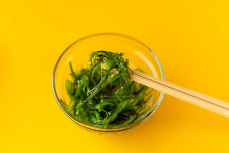 Téléchargez les photos : Salade chuka dans une assiette en verre avec baguettes - en image libre de droit