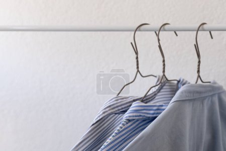 ropa en perchas, camisas azules sobre fondo blanco, compras, armario de ropa
