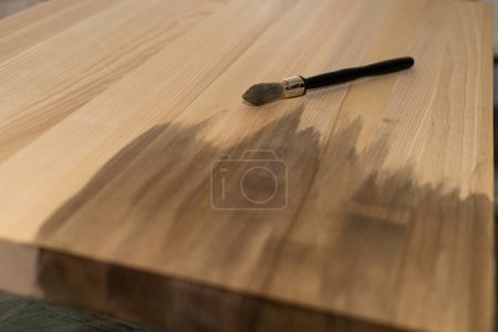Téléchargez les photos : Revêtement avec une huile de couleur pinceau d'un bouclier de frêne en bois - en image libre de droit
