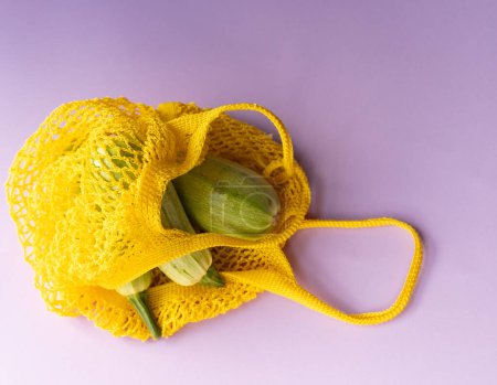 tres calabacines verdes en un tazón amarillo, bolsa ecológica