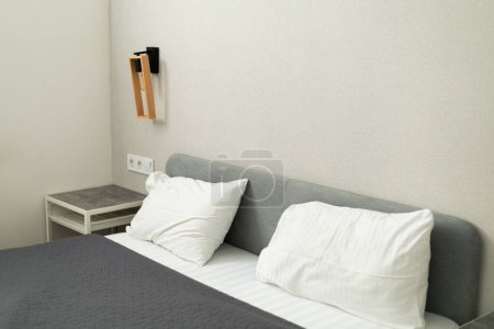 tête de lit avec oreillers blancs et couvre-lit gris dans la chambre