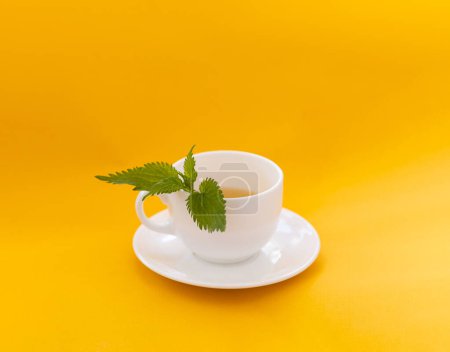 Téléchargez les photos : Une tasse de thé à l'ortie, tasse blanche - en image libre de droit