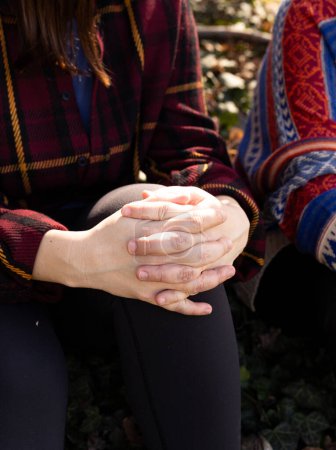 young woman's hands are folded in a lock on her knee