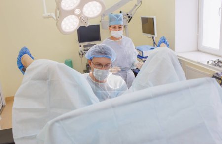 Téléchargez les photos : Un proctologue et une infirmière effectuent une opération dans la salle d'opération - en image libre de droit
