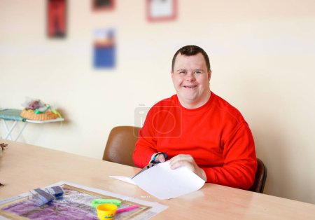 Foto de Un tipo con síndrome de Down hace costuras - Imagen libre de derechos