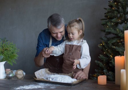 Foto de Una pequeña hija y su padre están preparando una Navidad estofada en la cocina con su azúcar en polvo. - Imagen libre de derechos