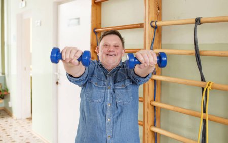 a man with down syndrome does sports with dumbbells in his hands