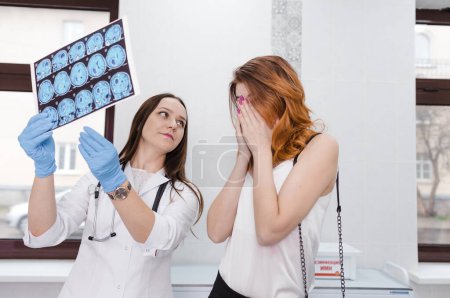 Téléchargez les photos : Un jeune malade en colère pleure en regardant une tomographie cérébrale. Tumeur cérébrale. - en image libre de droit