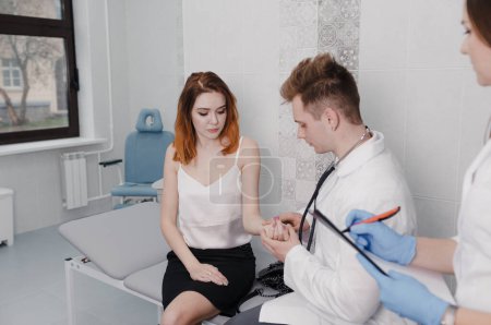Téléchargez les photos : Le médecin mesure le pouls du patient lors d'un rendez-vous à la clinique assis sur le canapé - en image libre de droit
