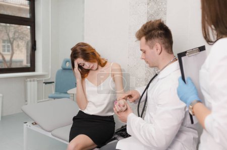 Téléchargez les photos : Un patient à la clinique se plaint au médecin de ne pas se sentir bien. le médecin mesure le pouls du patient assis dans le bureau - en image libre de droit
