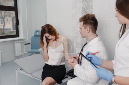 Téléchargez les photos : Un patient à la clinique se plaint au médecin de ne pas se sentir bien. le médecin mesure le pouls du patient assis dans le bureau - en image libre de droit