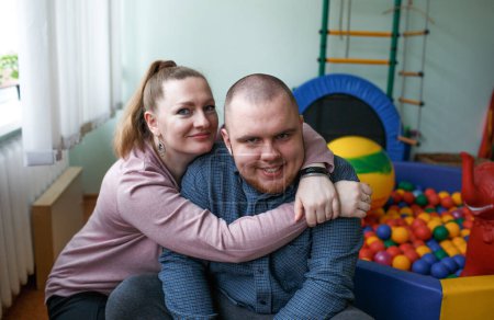 fürsorgliche Mutter umarmt ein Kind mit Autismus-Diagnose in einem Reha-Zentrum
