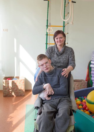 Photo for A boy with disabilities in a rehabilitation center with special needs next to his mother. - Royalty Free Image