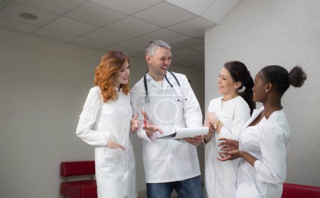 Téléchargez les photos : A group of medical staff communicate and laugh in the corridor of the clinic. - en image libre de droit