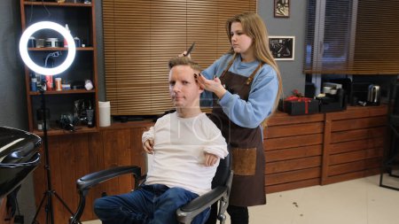 Photo for A man with disabilities in a white T-shirt does a haircut and hair styling in a barber shop. A full life for people with disabilities. - Royalty Free Image