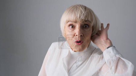 Téléchargez les photos : La vieille femme peut à peine entendre, isolée sur un fond blanc. - en image libre de droit