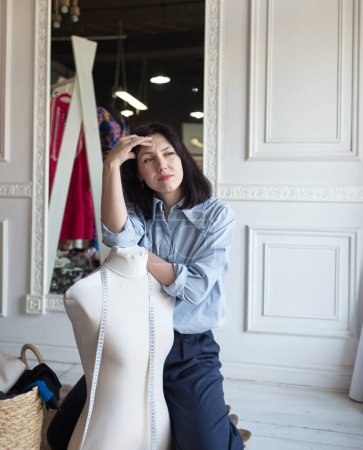 Foto de Una chica de diseño crea ropa en un taller, mide por un centímetro. - Imagen libre de derechos