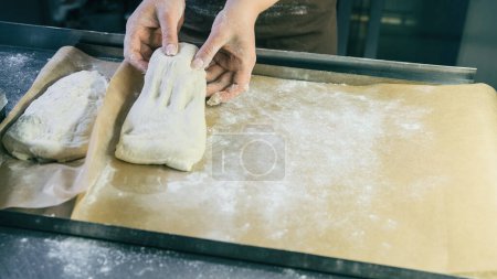 Téléchargez les photos : Cuire pour former de la pâte crue sur du papier sulfurisé pour préparer le pain - en image libre de droit