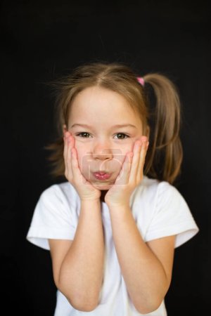 Foto de Divertida niña haciendo caras sobre un fondo oscuro. - Imagen libre de derechos