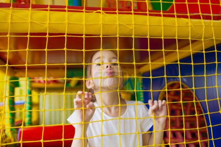 Téléchargez les photos : Petite fille frénésie montre la langue dans le centre de jeux pour enfants. - en image libre de droit