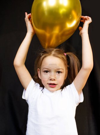 Foto de Divertida niña con un globo sobre un fondo oscuro. - Imagen libre de derechos