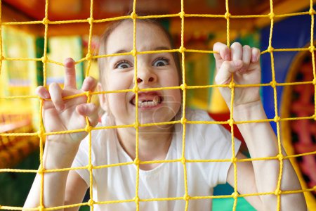 Téléchargez les photos : Une petite fille frémit dans un centre de jeux pour enfants. - en image libre de droit