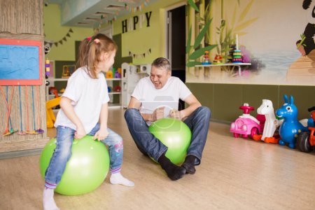 Foto de Padre e hija se divierten y juegan en el centro creativo de los niños, saltar en una pelota de gimnasia. - Imagen libre de derechos