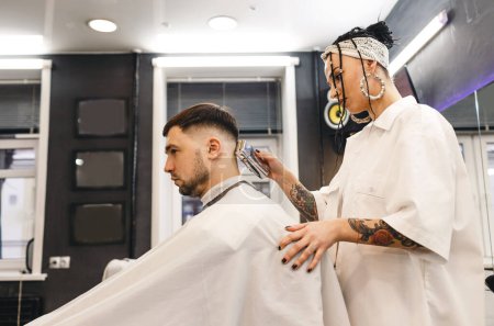 Foto de Un barbero le corta el pelo a un hombre en una peluquería. Peluquería profesional para hombres. Peluquería. - Imagen libre de derechos