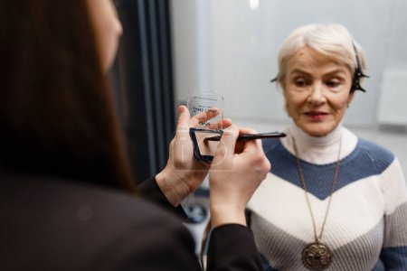 Téléchargez les photos : Une femme âgée rend visite à un maquilleur professionnel. Un maquilleur expérimenté fait du maquillage pour un client. - en image libre de droit