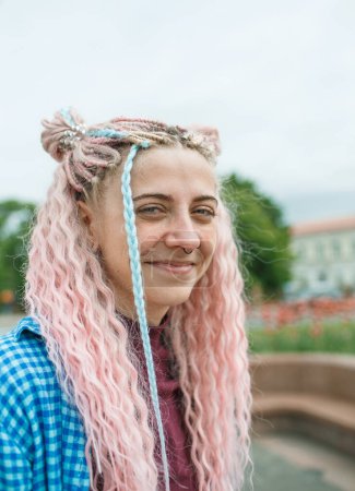 Foto de Muchacha atractiva en auriculares con pelo rosa y una camisa azul. - Imagen libre de derechos