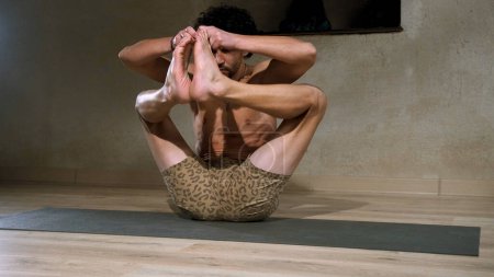 Téléchargez les photos : Un homme jeune et athlétique fait du yoga et effectue des asanas - en image libre de droit
